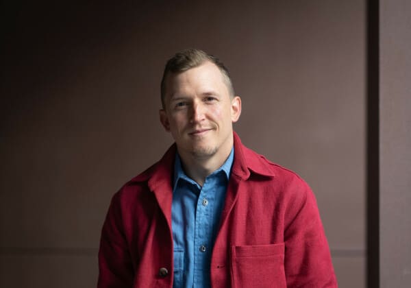 WooCommerce strategist, Piers tincknell, faces camera wearing red jacket and blue shirt