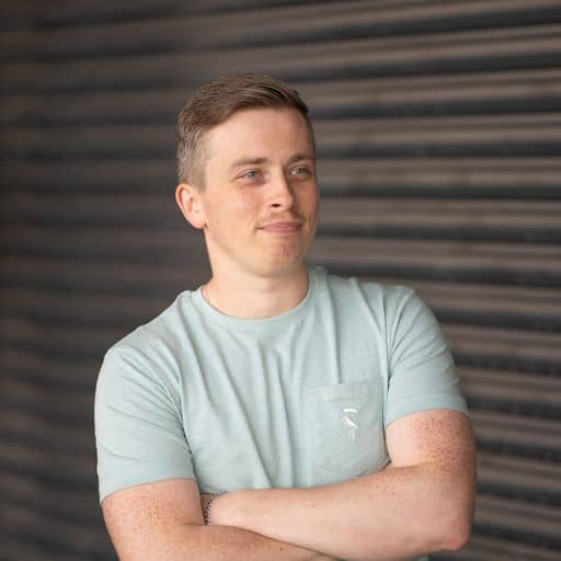 Colin looking away from camera in front of an industrial backdrop