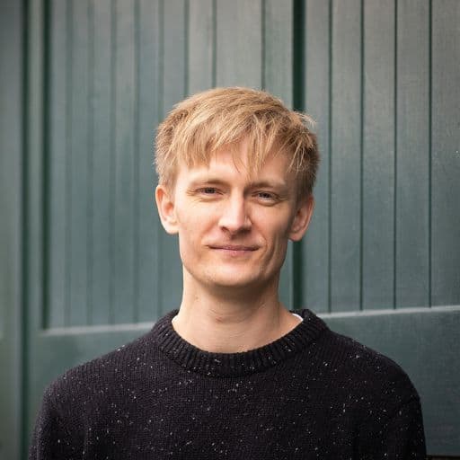 Duncan looking at camera in front of a green industrial backdrop