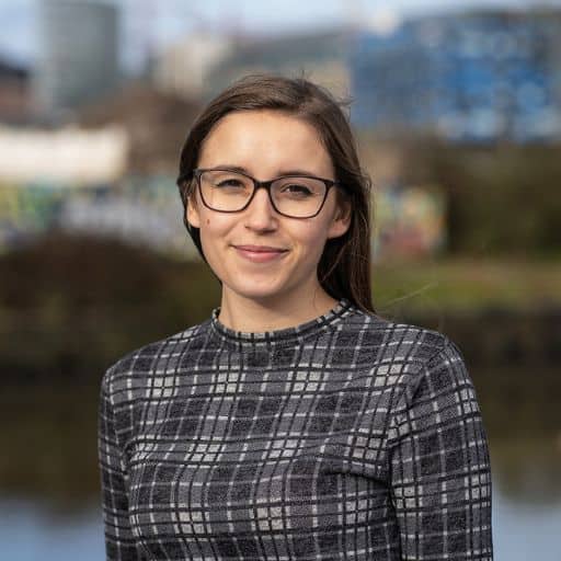 Jade Sperrin looking at camera in front of a body of water