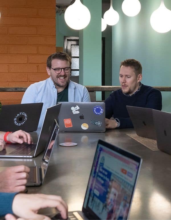 Team members look at laptops in meeting