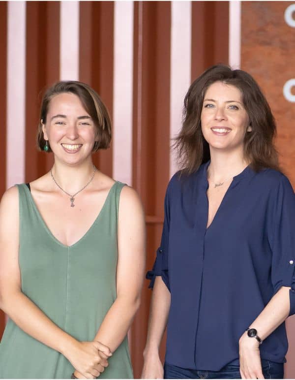 Team members Zoe and Julia stand in front of a metal background