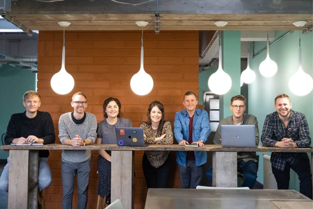 Seven members of the Atomic Smash team stand in creative workspace