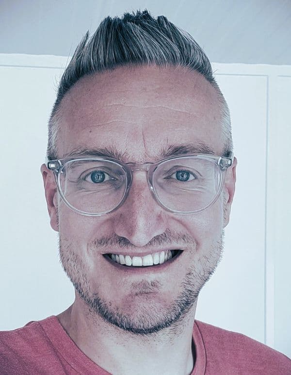 Man wearing glasses smiles at the camera