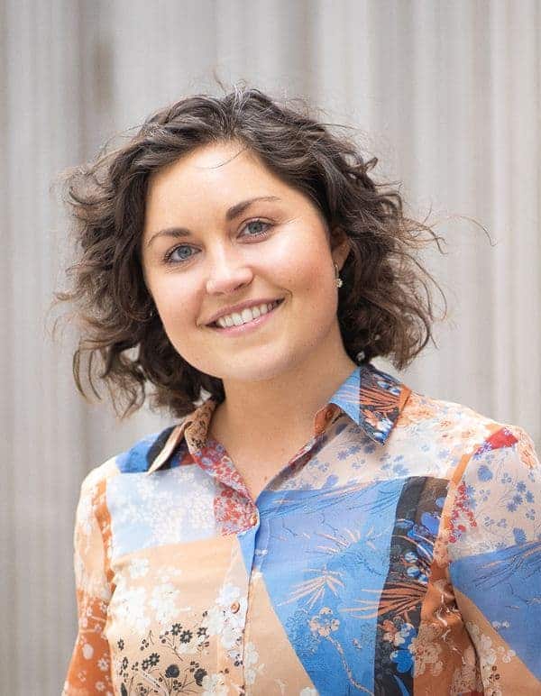 Woman in colourful blouse smiles outdoors