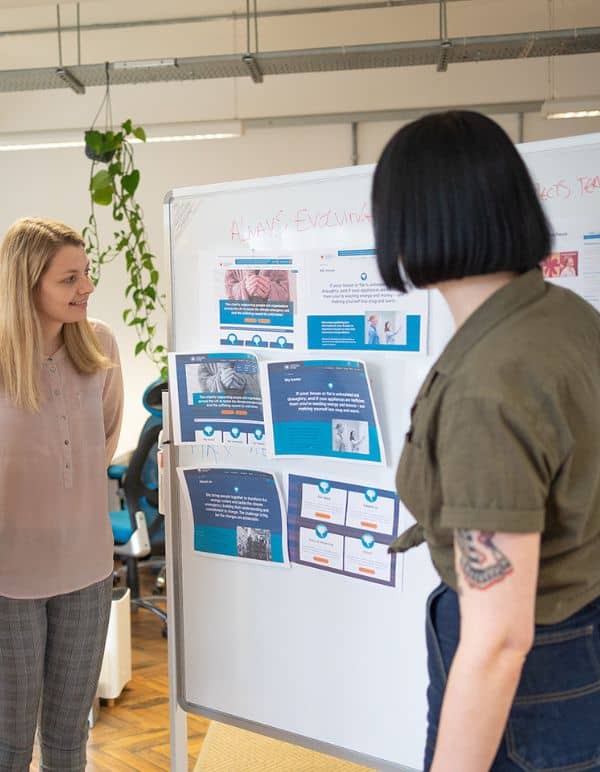 Two women looking at print outs of website and planning website evolution