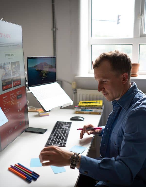 Piers, Client Director at Shopify agency Atomic Smash, working at desk using both laptop and post it notes for Shopify growth strategy