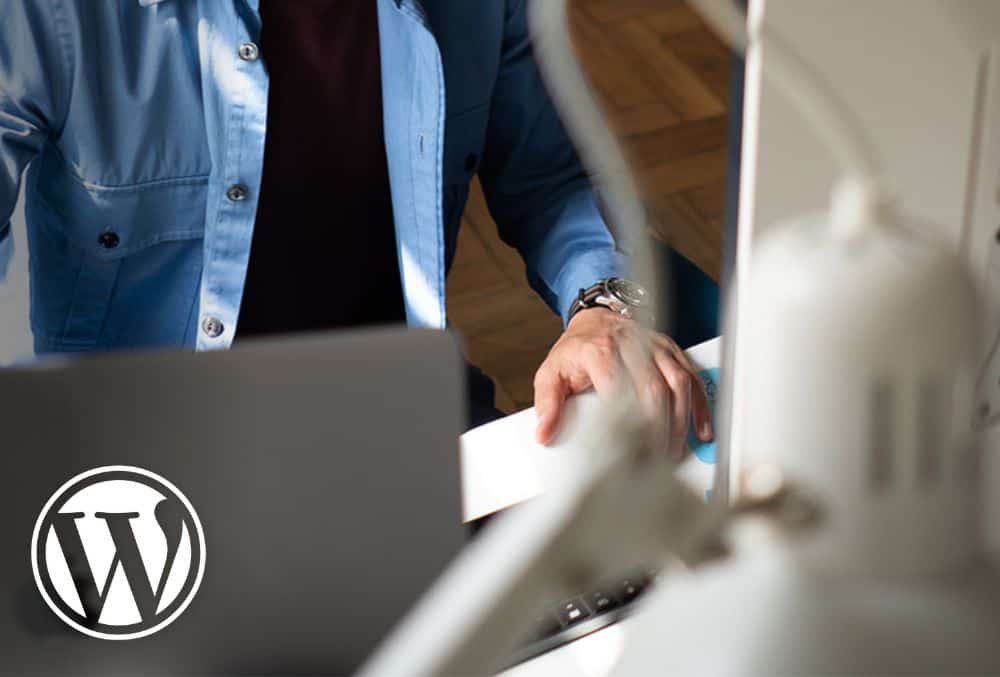 Image of Atomic Smash WordPress agency developer working on laptop and computer screen plus WordPress logo