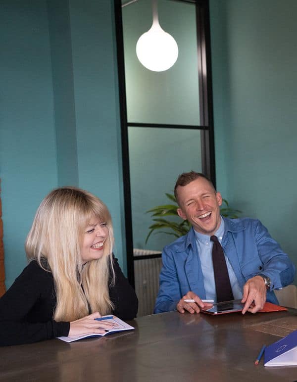 Two colleagues laughing whilst discussing projects