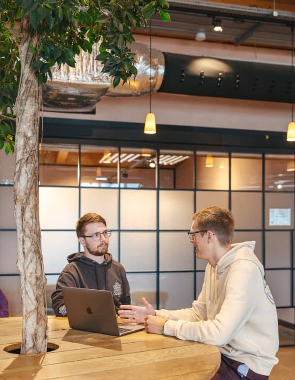 Two team members talking by a laptop